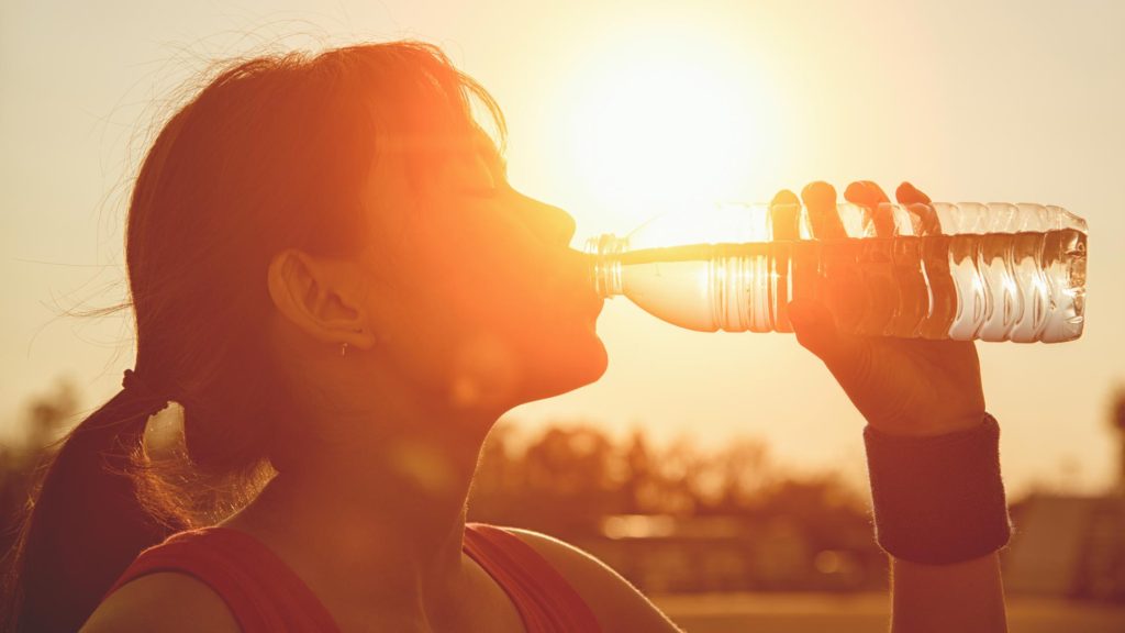 Asian woman drinking from a water bottle in the summer heat