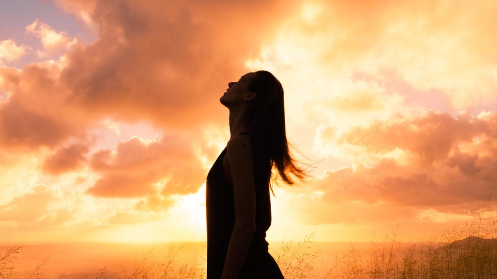 Woman cast in shadow against a beautiful sunrise
