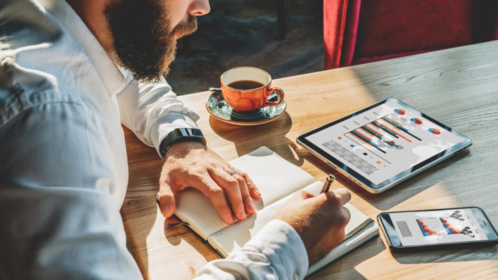 Bearded male working on multiple devices while planning his finances