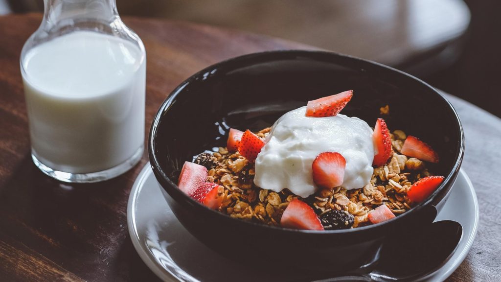 Glass of milk next to a nutritious oats and fruit breakfast
