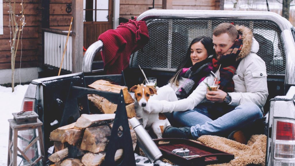 A man and woman enjoying a winter picnic in the bed of a truck