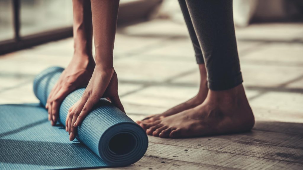 A female rolling out a blue yoga mat