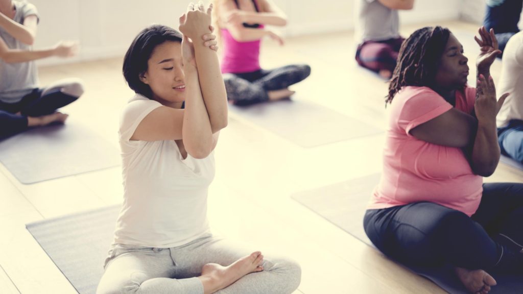 Multiple women of varying nationalities and cultures in a yoga class